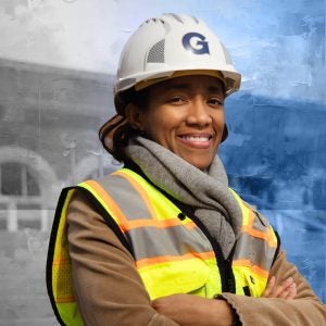 Una mujer negra con un chaleco amarillo sonríe mientras usa un casco 