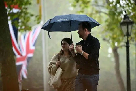 Getty Images Turistas se refugian de la lluvia bajo paraguas mientras caminan por The Mall durante un aguacero en el centro de Londres el 10 de septiembre de 2025.