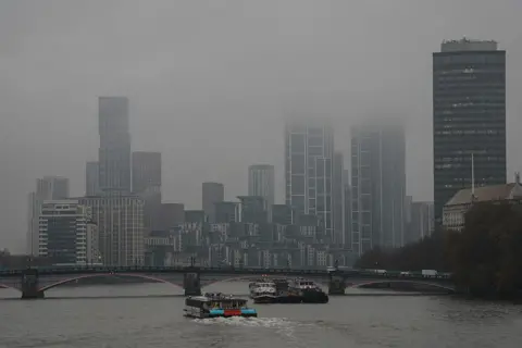 Getty Images Un catamarán navega por el Támesis hacia los altos edificios parcialmente oscurecidos por las nubes de Londres. 