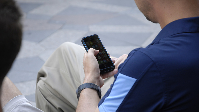 Una persona usando un iPhone en la calle.