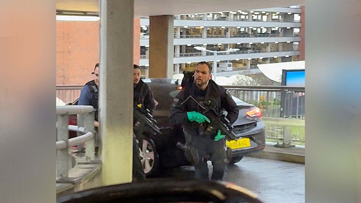 Oficiales armados corriendo en el estacionamiento.