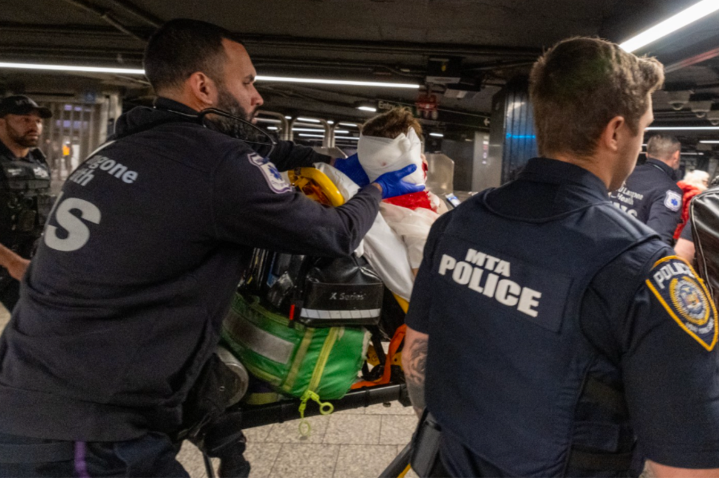 Los servicios de emergencia y la policía de la MTA atienden a una víctima en camilla en una estación de metro.