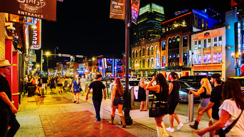 Los turistas caminan por el centro de Nashville en Broadway por la noche