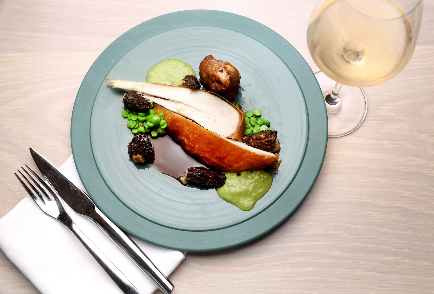 Pollo de piel crujiente con colmenillas y guisantes.